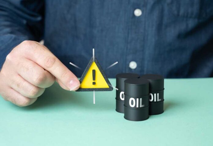 A person holding a warning sign next to oil barrels