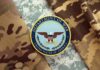 Patriot Shortage Panic? Department of War insignia on camouflage fabric
