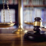 Hot Mic Nails Judge In ICE Showdown Scales and gavel on a judges desk.