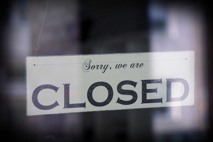 Sign,Saying,Sorry,We,Are,Closed,,Behind,Glass,With,Reflection, A sign hanging in a window that reads 'Sorry, we are CLOSED'