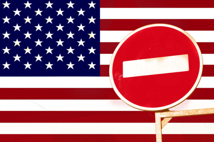 Prohibiting,Sign,Of,Entry,Against,The,Background,Of,The,American A no entry sign in front of the American flag