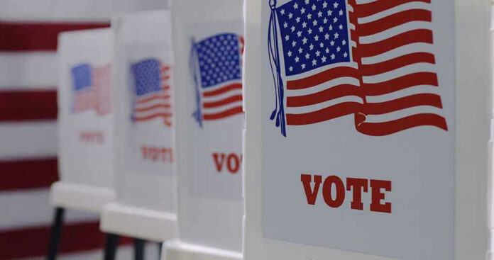 1743370412 Voting booths with American flags and VOTE signs.