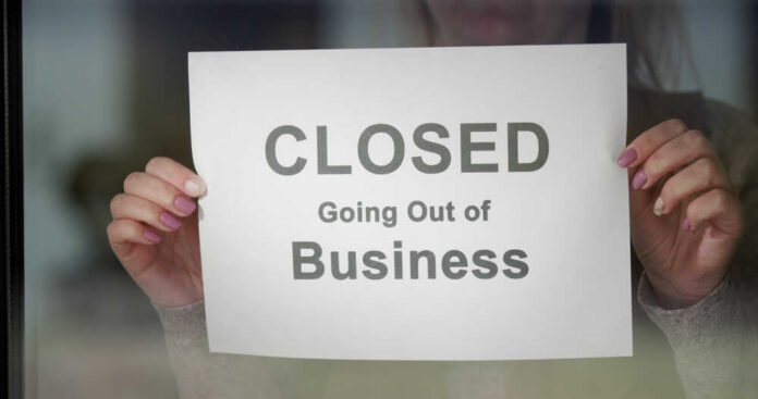 Worker,Hangs,A,Banner,Closed,Going,Out,Of,Business,On A person holding a sign that reads 'CLOSED Going Out of Business'