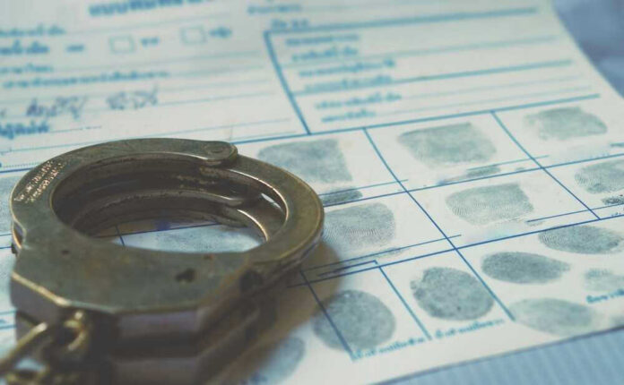 shutterstock_2291869477 Handcuffs on a fingerprint document.