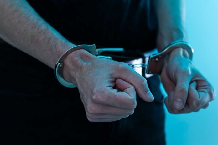 Male,Hands,In,Handcuffs,Black,Background Close-up of hands in handcuffs