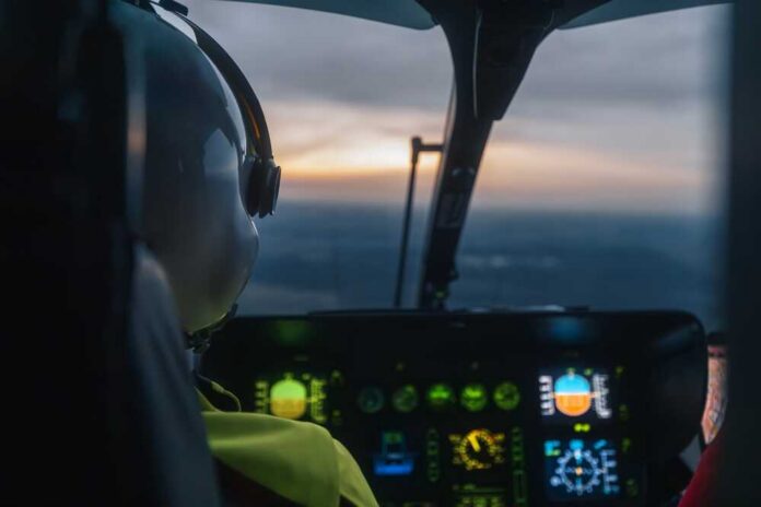 Pilot,Of,Helicopter,Emergency,Medical,Service,Flying,Over,Landscape,At Pilot's view from a helicopter cockpit during sunset