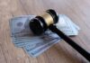 Judge’s gavel resting on a stack of US hundred-dollar bills