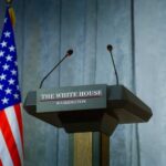 Chilling Plea To Beau Stuns Washington Press podium with the White House sign and an American flag in the background