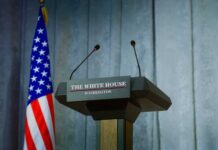 Press podium with the White House sign and an American flag in the background