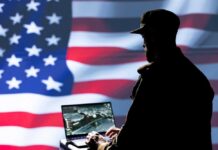 Silhouette of a person using a laptop before a large US flag