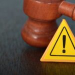 Judge's gavel beside yellow warning triangle sign