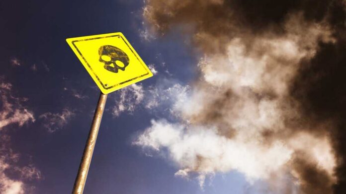 Yellow warning sign with skull symbol under dramatic cloudy sky