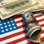 FBI Dangles $25K — Details HERE! A roll of hundred dollar bills placed on an American flag