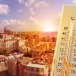 Thermometer displaying high temperature against a bright sun