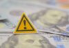 Deficit Explosion Tops $2 Trillion A warning sign placed on top of U.S. dollar bills