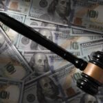 Judge’s gavel on scattered US hundred-dollar bills