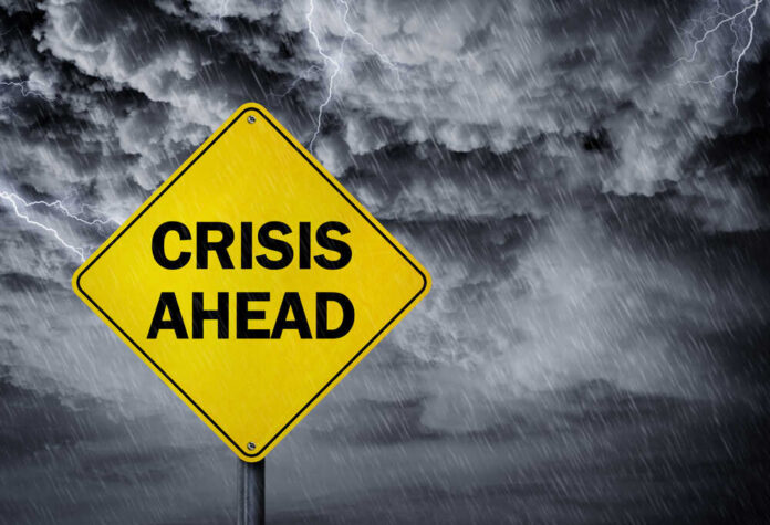 Crisis,Ahead,Sign,In,A,Rain,Storm,Concept,For,Financial A yellow warning sign that reads 'CRISIS AHEAD' against a stormy sky