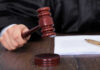 Judges hand holding gavel next to documents.