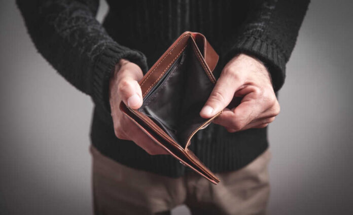 Man,Holding,Empty,Wallet.,No,Money A hand holding a diesel fuel nozzle at a gas station
