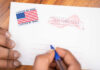 UPDATE: Supreme Court Showdown Over THESE Ballots Hands addressing an official election mail envelope