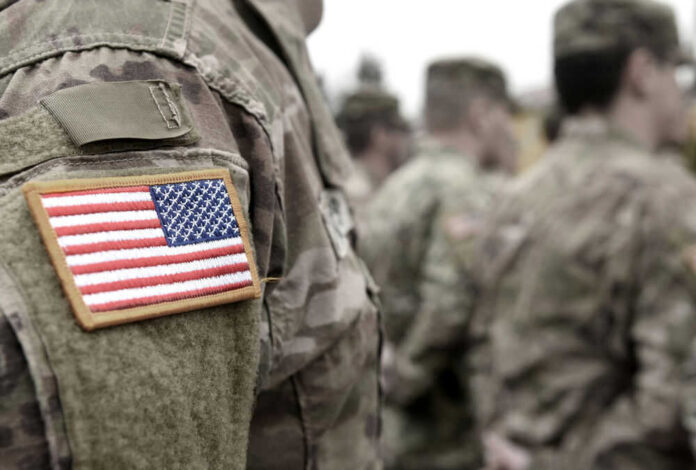 shutterstock_1836976885 Soldiers in camouflage uniforms with American flag patches.