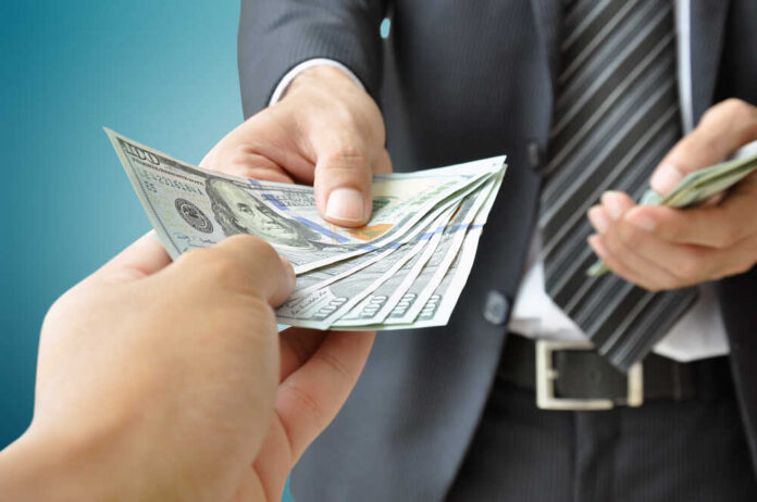 Hand,Receiving,Money,From,Businessman,-,United,States,Dollar,(usd) A person handing over a stack of cash to another individual in a suit