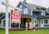 HAPPENING NOW: Housing Slide Speeds Up For sale sign in front of a house with potential buyers discussing