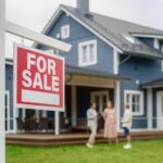 HAPPENING NOW: Housing Slide Speeds Up For sale sign in front of a house with potential buyers discussing