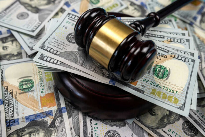 shutterstock_2264281137 Gavel on pile of hundred dollar bills