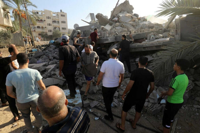 shutterstock_2374656285 People search through rubble of a collapsed building