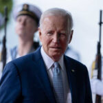 Joe Biden stands in front of uniformed honor guards