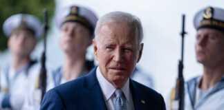 Joe Biden stands in front of uniformed honor guards