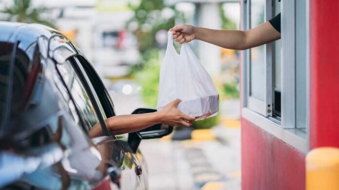 Young,Man,Receiving,Coffee,At,Drive,Thru,Counter.,,Drive,Thru Drive-thru window handing a takeout bag to a car