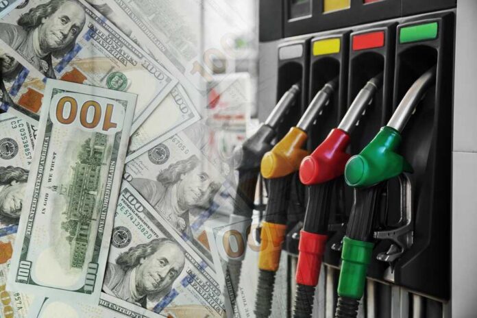 Fuel,Price.,Gas,Filling,Station,And,Dollar,Banknotes,,Double,Exposure Fuel pump nozzles next to spread of U.S. hundred-dollar bills