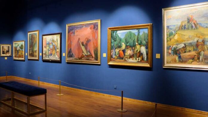 Art gallery showcasing various colorful paintings on a blue wall