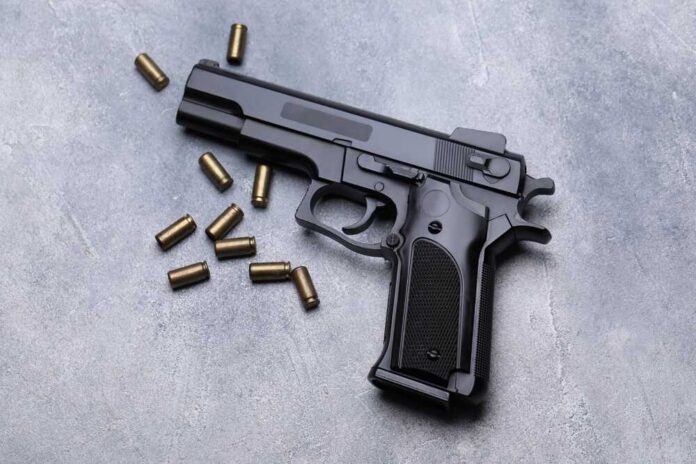 Bullets,And,Gun,On,Grey,Table,,Flat,Lay Black semi-automatic pistol with scattered brass cartridges on a gray surface