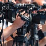 AI Layoffs Targeted New Moms? television cameras on tripods at a media event