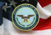 GOP Rebel Moves to Nail Defense Chief Emblem of the Department of War on a background of the American flag