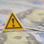 Staggering Payouts Ignite Rural Frenzy A warning sign placed on top of U.S. dollar bills