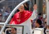 Catholic clergyman in red vestments waving from a popemobile