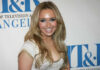 Smiling woman with long blonde hair at a media event
