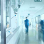 Ebola Alarm Blasts — What’s Being Hidden? Hospital corridor with IV drip and healthcare worker.
