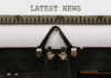 Iconic Food Mascot Goes Silent – Why? Close-up of a typewriter with a sheet of paper displaying the words 'LATEST NEWS'