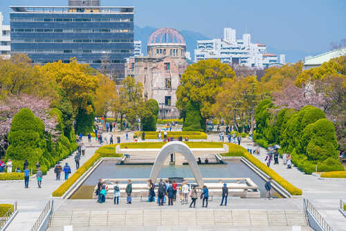 Hiroshima,Peace,Memorial,Park,In,Japan,With,Blue,Sky Visitors at Hiroshima Peace Memorial Park with cherry blossoms and memorial structures