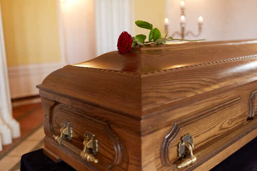 Funeral,And,Mourning,Concept,-,Red,Rose,Flower,On,Wooden A wooden casket with a red rose placed on top