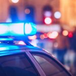 Buried Suitcase Murder Twist Shocks Investigators Close-up of a police car with blue emergency lights in a city at night