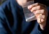 Hand holding a small plastic bag with white powder