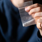 Hand holding a small plastic bag with white powder