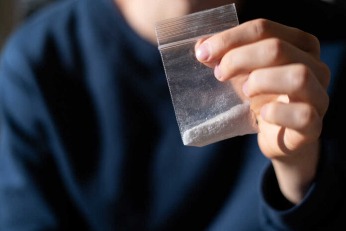 Hand holding a small plastic bag with white powder