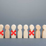 Wooden human figures in a row with red X marks on some